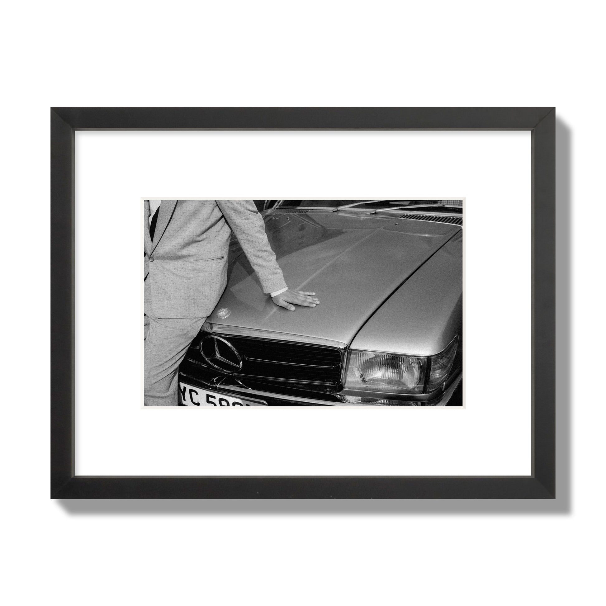 Fine art black & white photograph of a well dressed man leaning on a vintage Mercedes. Archival pigment print, small size, black frame.