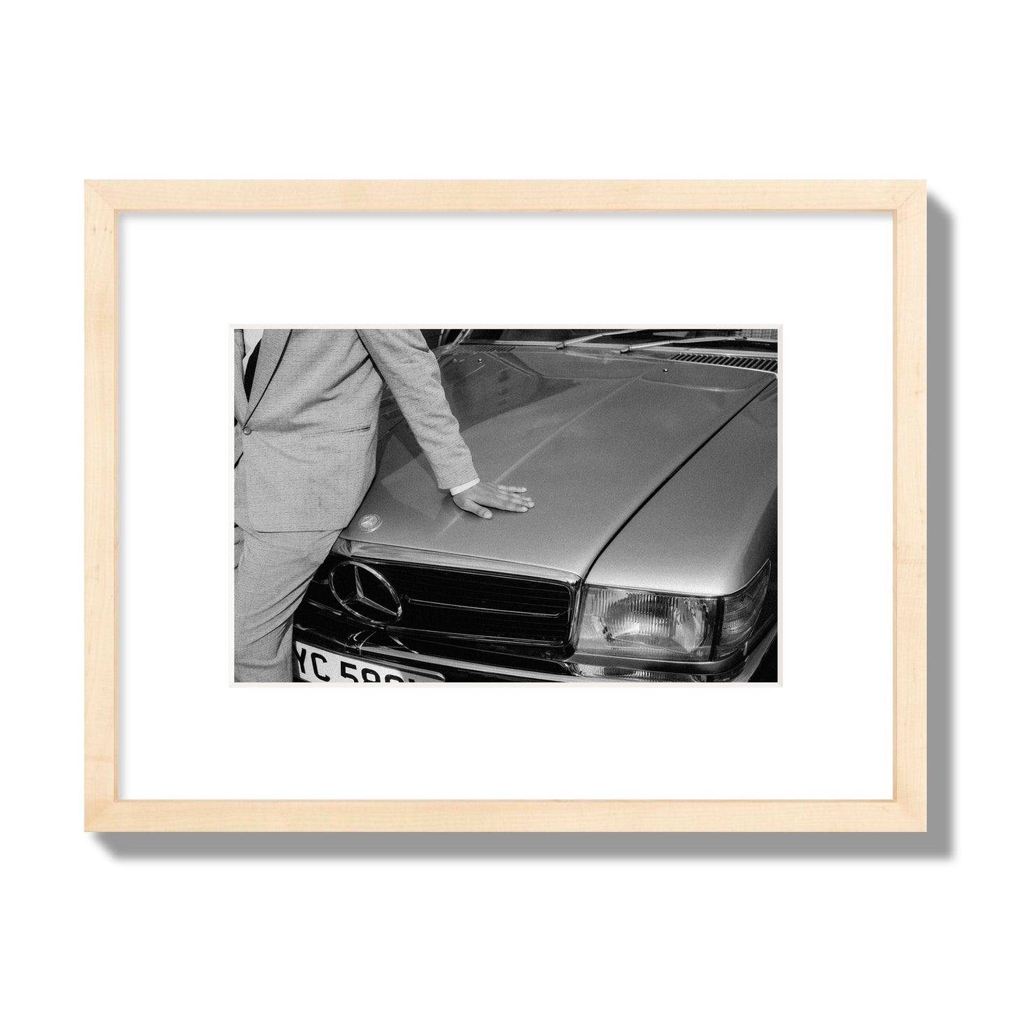 Fine art black & white photograph of a well dressed man leaning on a vintage Mercedes. Archival pigment print, small size, natural wood frame.