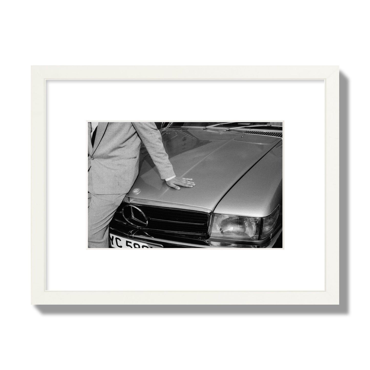 Fine art black & white photograph of a well dressed man leaning on a vintage Mercedes. Archival pigment print, small size, white frame.