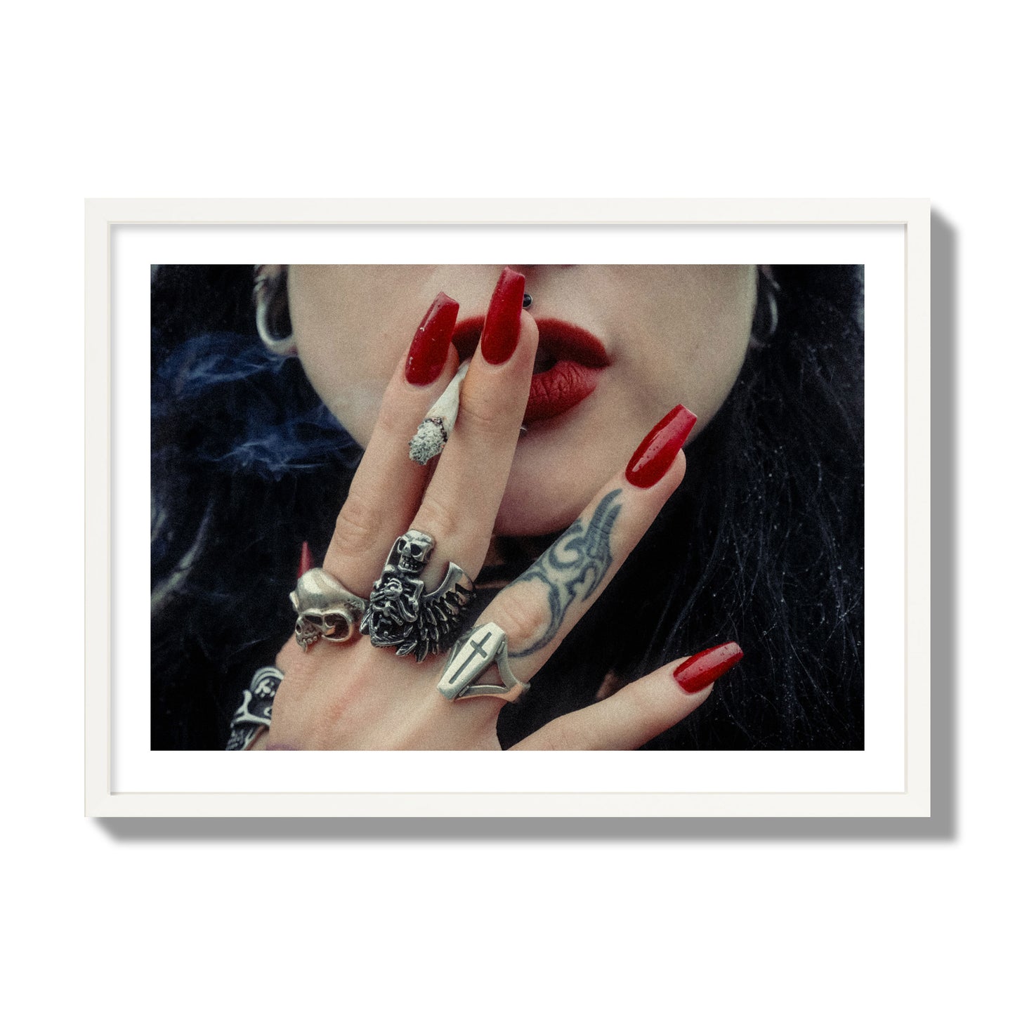 Fine art close-up photograph of a woman smoking, her hands covered with chunky rings and tattoos. Archival pigment print, giant size, white frame.