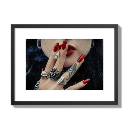 Fine art close-up photograph of a woman smoking, her hands covered with chunky rings and tattoos. Archival pigment print, medium size, black frame.
