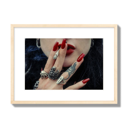 Fine art close-up photograph of a woman smoking, her hands covered with chunky rings and tattoos. Archival pigment print, medium size, natural wood frame.