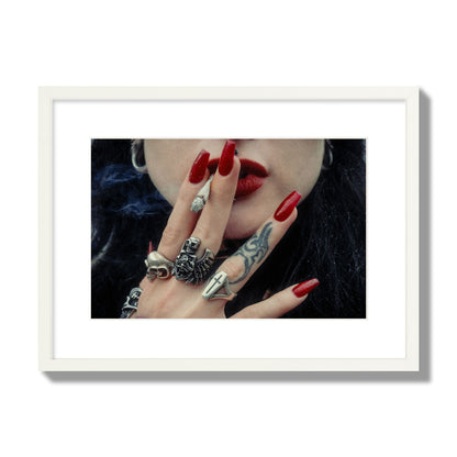 Fine art close-up photograph of a woman smoking, her hands covered with chunky rings and tattoos. Archival pigment print, medium size, white frame.