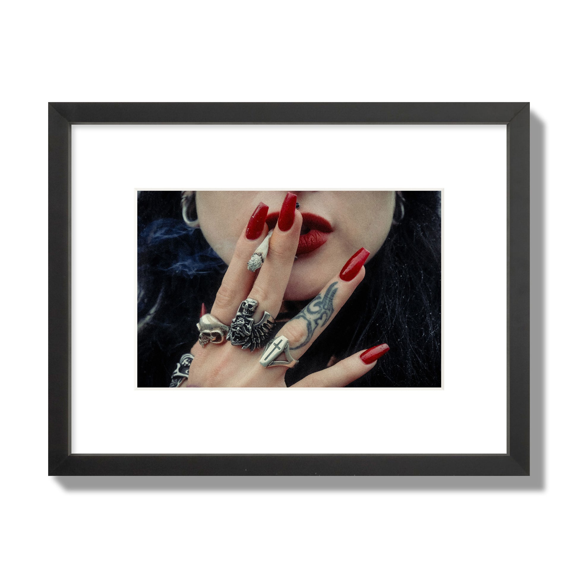 Fine art close-up photograph of a woman smoking, her hands covered with chunky rings and tattoos. Archival pigment print, small size, black frame.