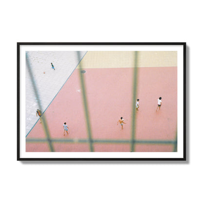 Fine art street photograph of a geometric outdoor scene in Portugal with people playing soccer on a pink field, archival pigment print, collector size, black frame.