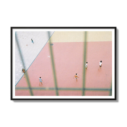 Fine art street photograph of a geometric outdoor scene in Portugal with people playing soccer on a pink field, archival pigment print, gallery size, black frame.