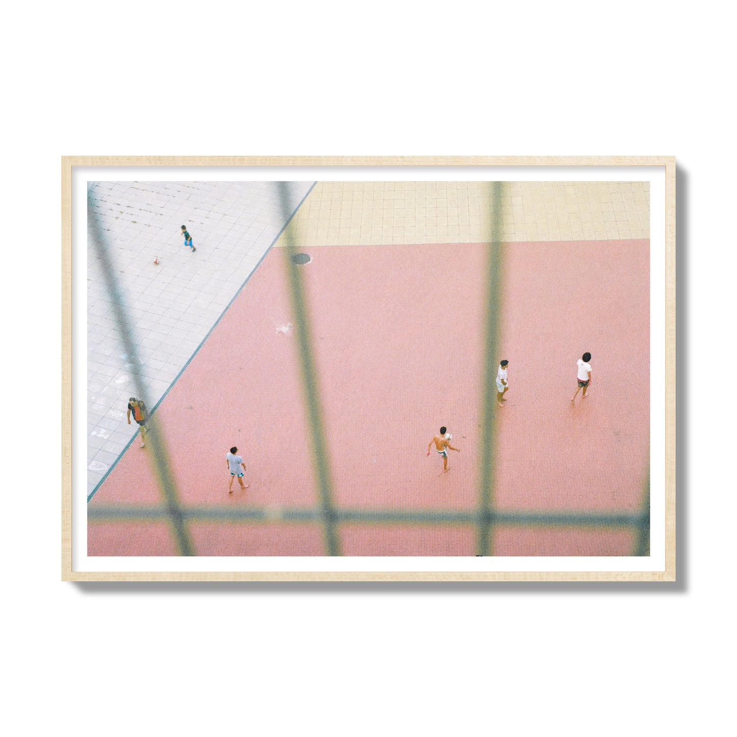 Fine art street photograph of a geometric outdoor scene in Portugal with people playing soccer on a pink field, archival pigment print, gallery size, natural wood frame.