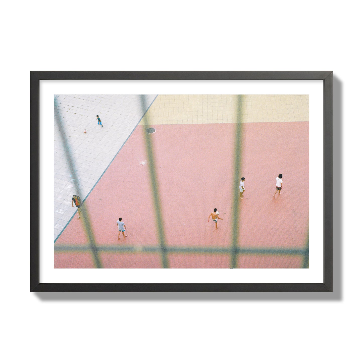 Fine art street photograph of a geometric outdoor scene in Portugal with people playing soccer on a pink field, archival pigment print, giant size, black frame.
