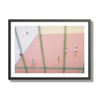 Fine art street photograph of a geometric outdoor scene in Portugal with people playing soccer on a pink field, archival pigment print, giant size, black frame.