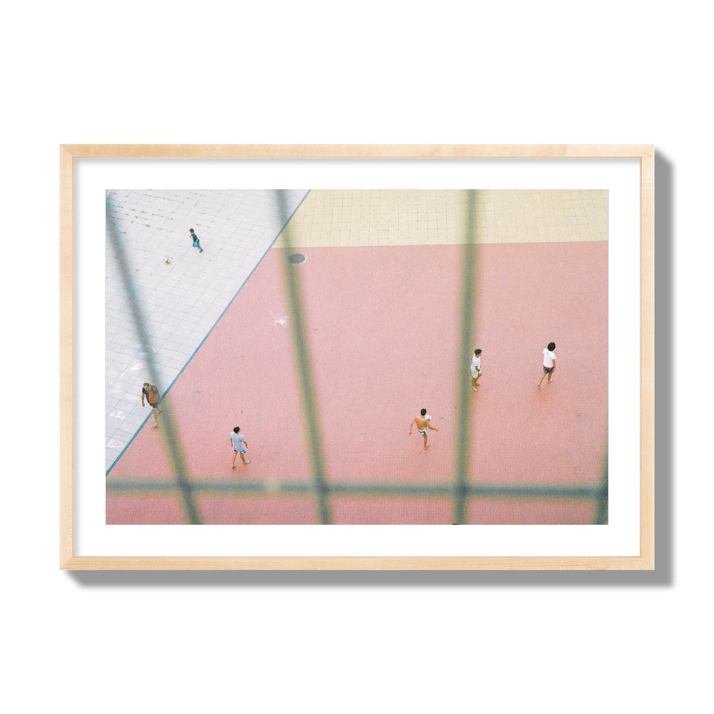 Fine art street photograph of a geometric outdoor scene in Portugal with people playing soccer on a pink field, archival pigment print, giant size, natural wood frame.