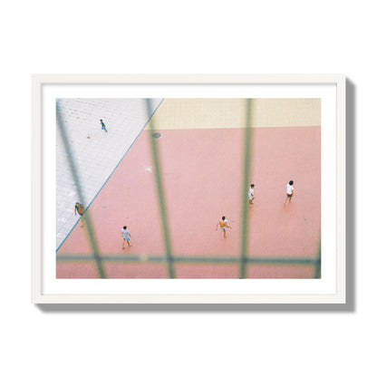 Fine art street photograph of a geometric outdoor scene in Portugal with people playing soccer on a pink field, archival pigment print, giant size, white frame.