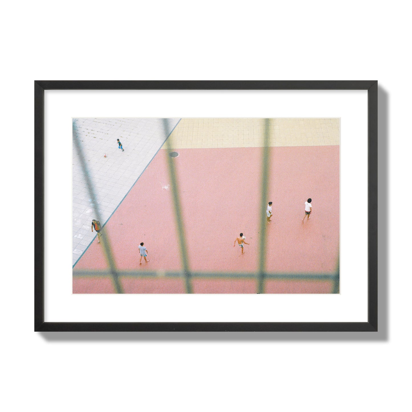 Fine art street photograph of a geometric outdoor scene in Portugal with people playing soccer on a pink field, archival pigment print, large size, black frame.