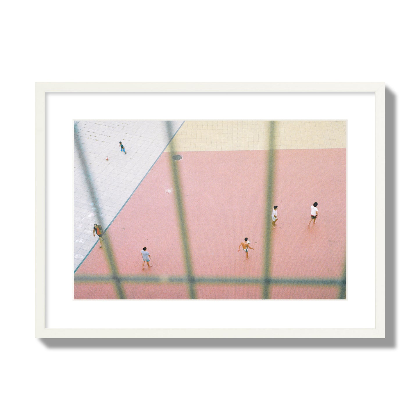 Fine art street photograph of a geometric outdoor scene in Portugal with people playing soccer on a pink field, archival pigment print, large size, white frame.
