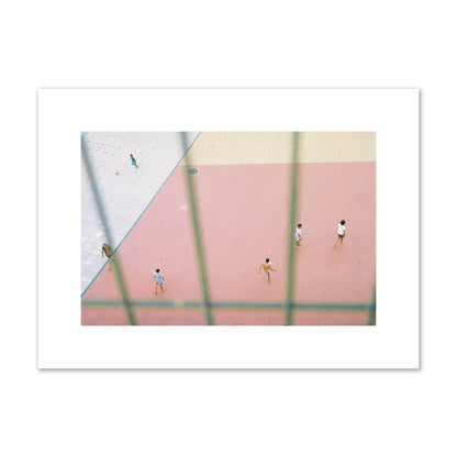 Fine art street photograph of a geometric outdoor scene in Portugal with people playing soccer on a pink field, archival pigment print, medium size, print.