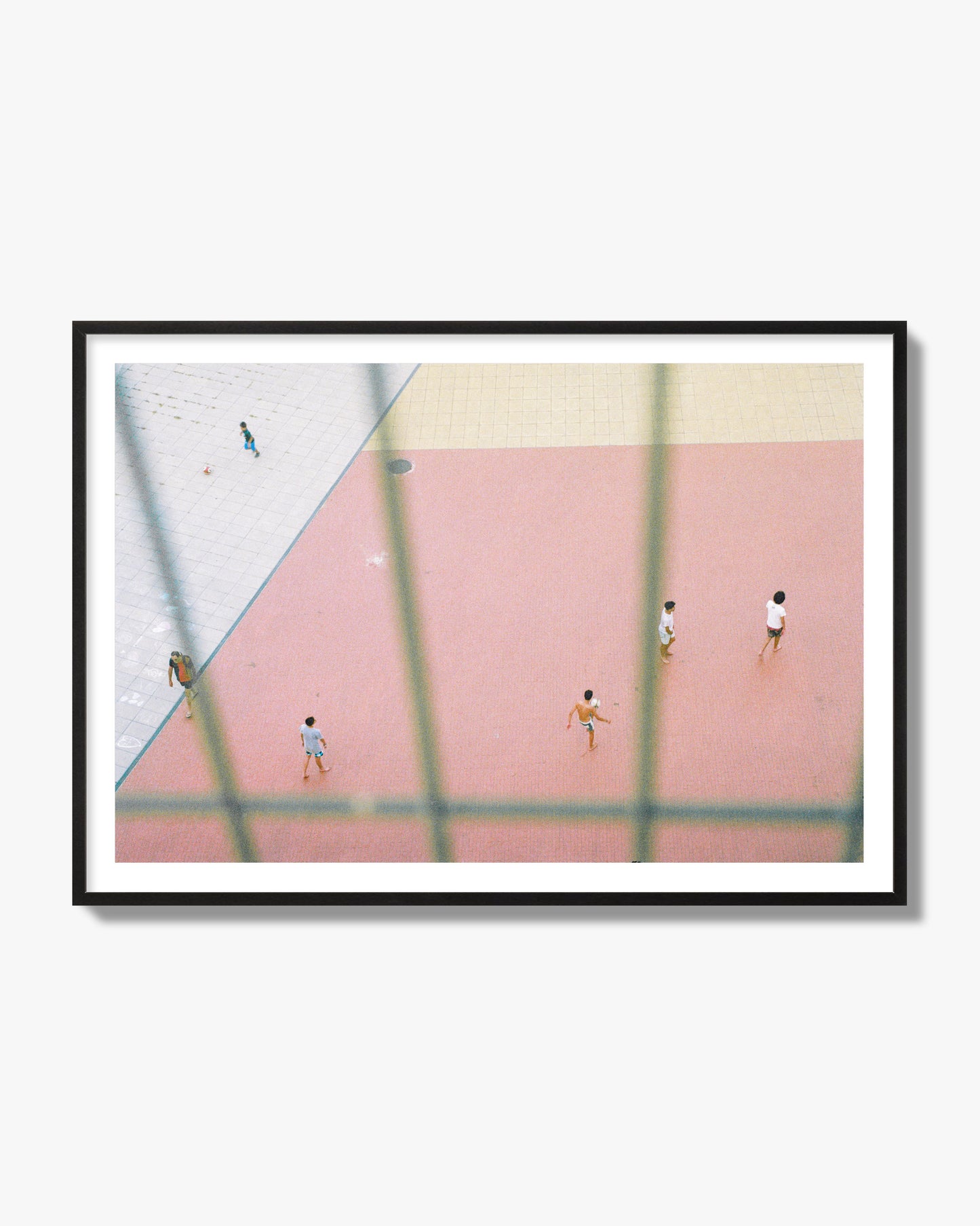Fine art street photograph of a geometric outdoor scene in Portugal with people playing soccer on a pink field, archival pigment print, black frame.