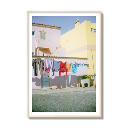 Fine art street photograph of a colorful outdoor scene in Portugal with clothes hanging on a line, archival pigment print, collector size, natural wood frame.