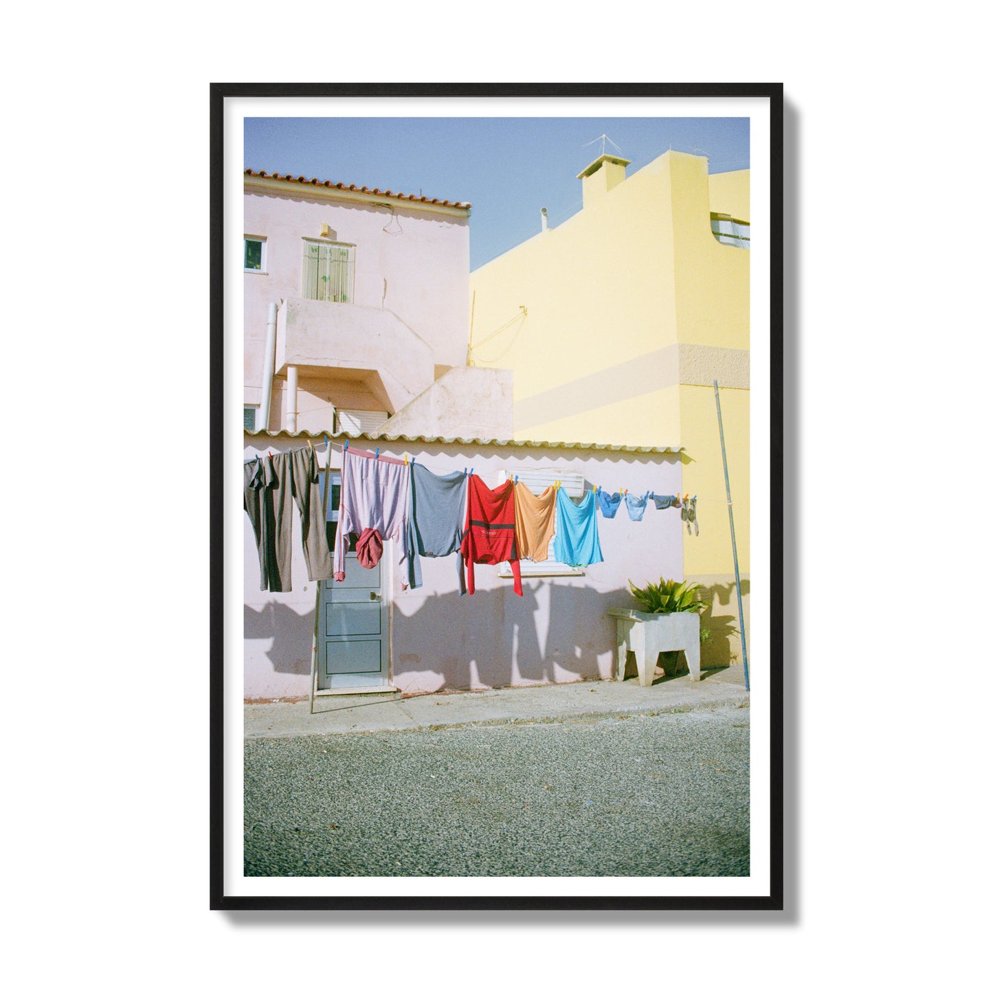 Fine art street photograph of a colorful outdoor scene in Portugal with clothes hanging on a line, archival pigment print, gallery size, black frame.