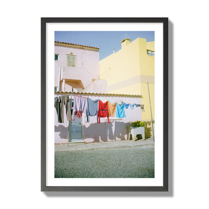 Fine art street photograph of a colorful outdoor scene in Portugal with clothes hanging on a line, archival pigment print, giant size, black frame.