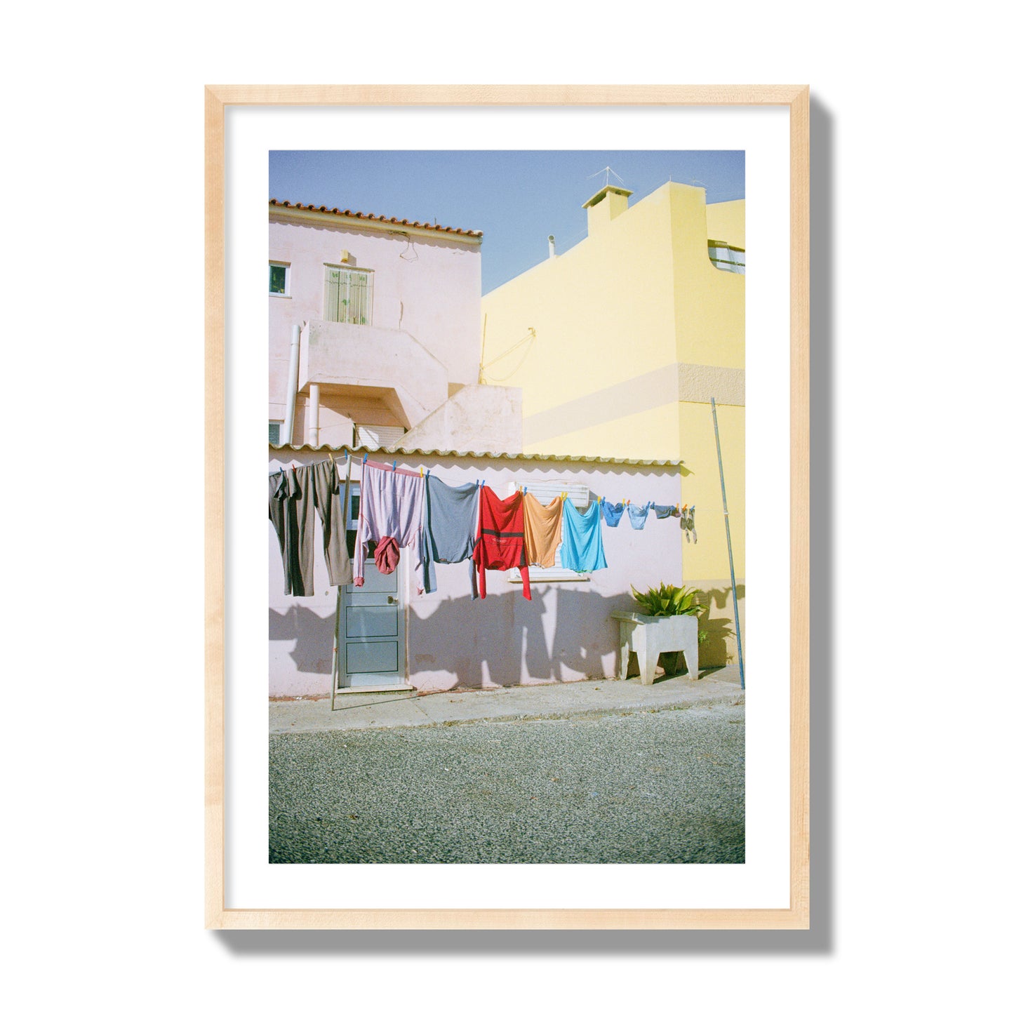 Fine art street photograph of a colorful outdoor scene in Portugal with clothes hanging on a line, archival pigment print, giant size, natural wood frame.