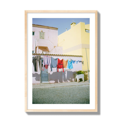 Fine art street photograph of a colorful outdoor scene in Portugal with clothes hanging on a line, archival pigment print, giant size, natural wood frame.