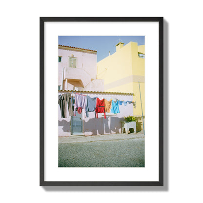 Fine art street photograph of a colorful outdoor scene in Portugal with clothes hanging on a line, archival pigment print, large size, black frame.