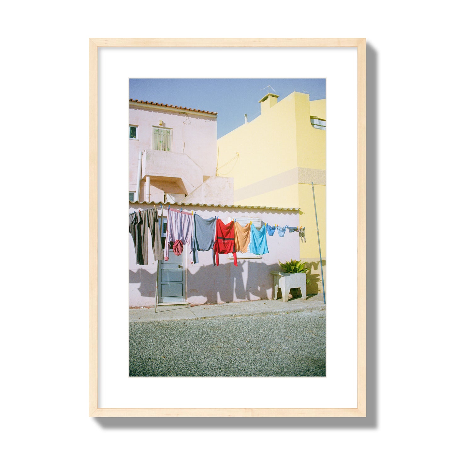 Fine art street photograph of a colorful outdoor scene in Portugal with clothes hanging on a line, archival pigment print, large size, natural wood frame.