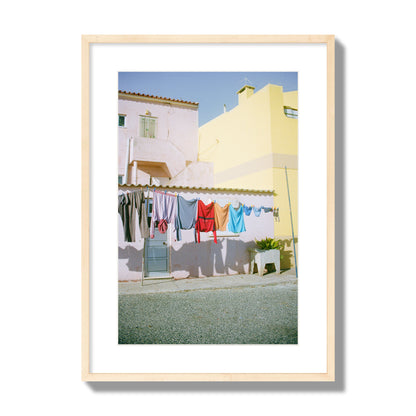 Fine art street photograph of a colorful outdoor scene in Portugal with clothes hanging on a line, archival pigment print, large size, natural wood frame.