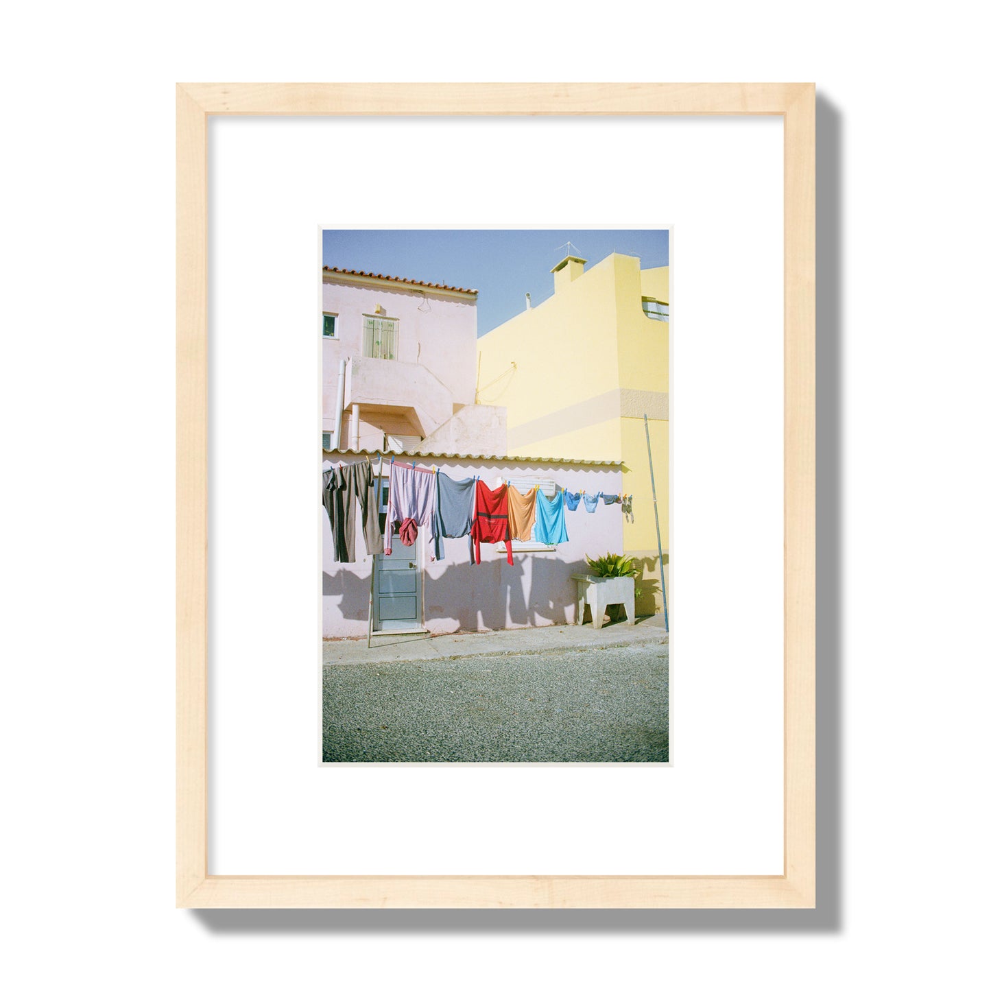 Fine art street photograph of a colorful outdoor scene in Portugal with clothes hanging on a line, archival pigment print, small size, natural wood frame.