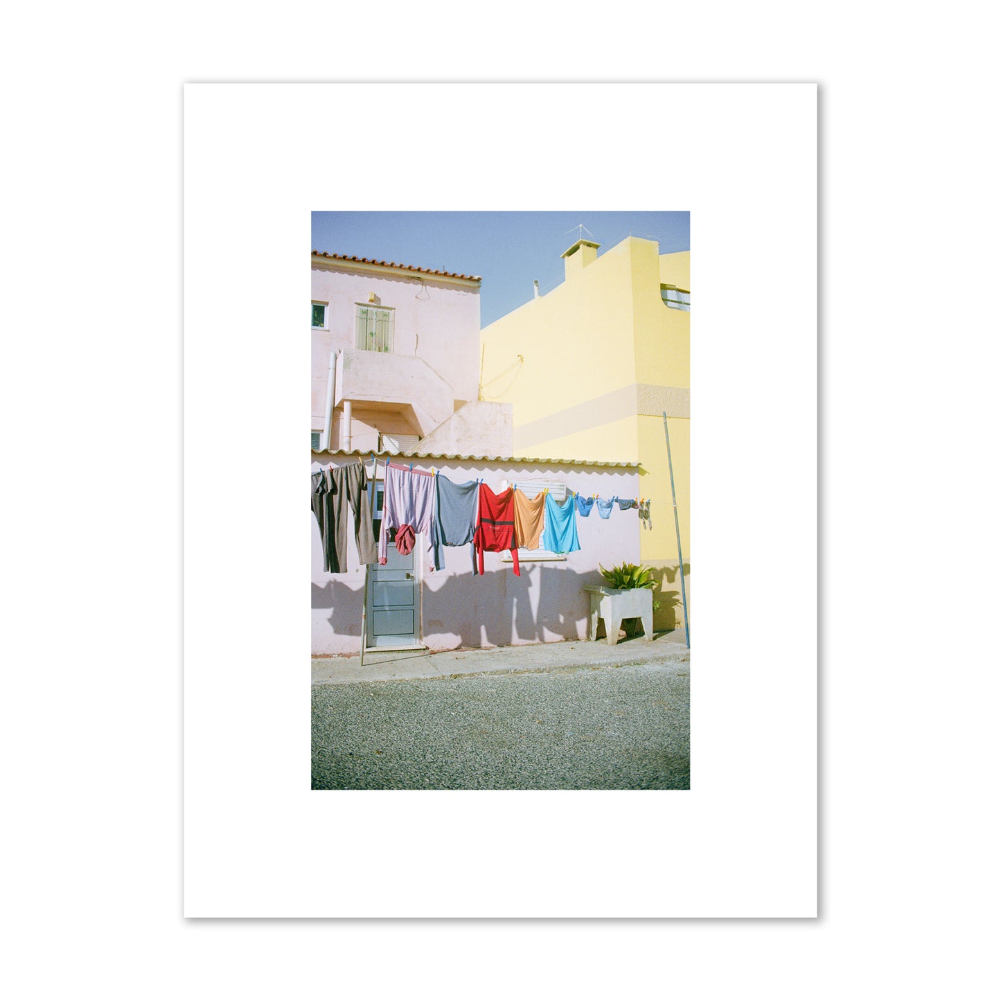 Fine art street photograph of a colorful outdoor scene in Portugal with clothes hanging on a line, archival pigment print, small size, print.