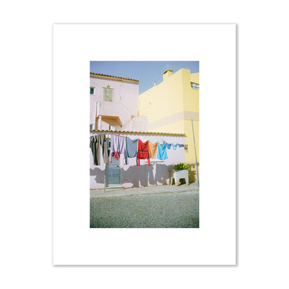 Fine art street photograph of a colorful outdoor scene in Portugal with clothes hanging on a line, archival pigment print, small size, print.