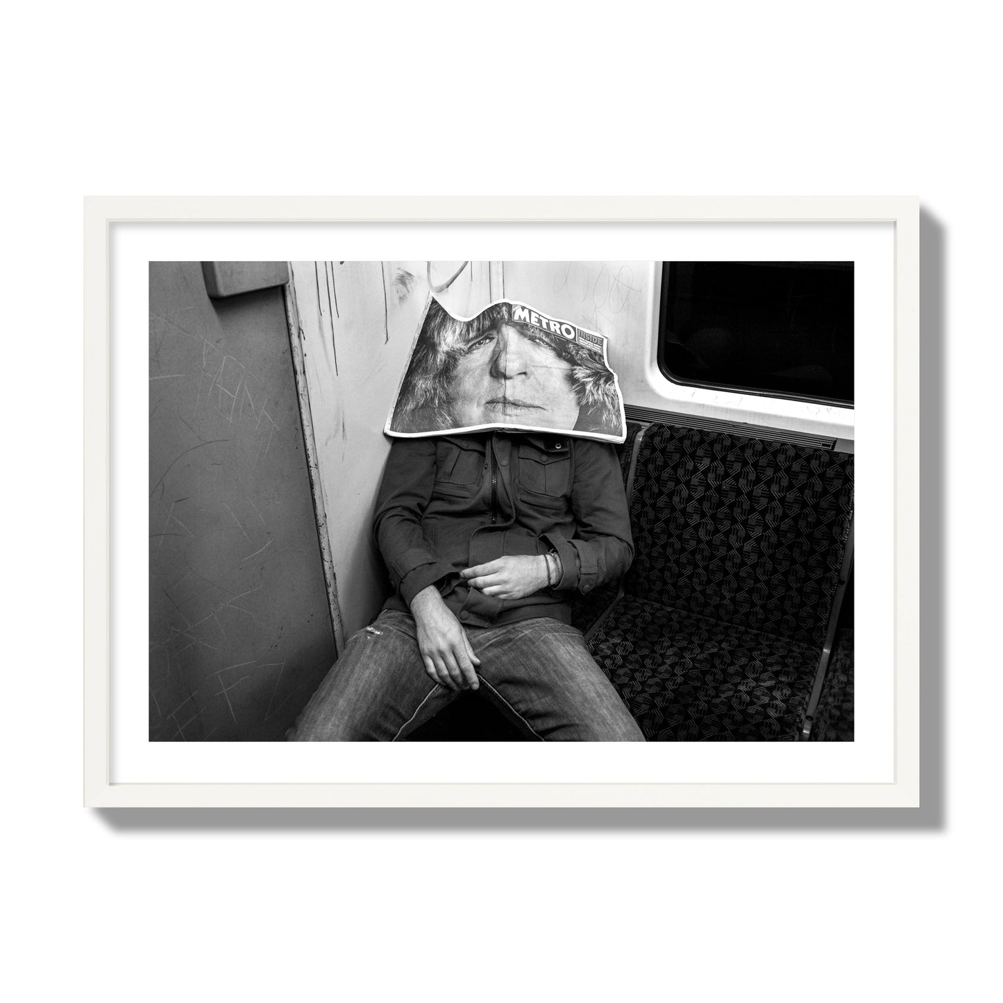 Fine art photograph of a man asleep on the subway with a newspaper covering their face, archival pigment print, giant size, white frame.