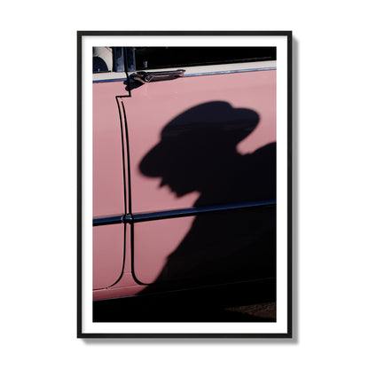 Fine art photograph of a man's shadow cast on a pink retro car, archival pigment print, collector size, black frame.