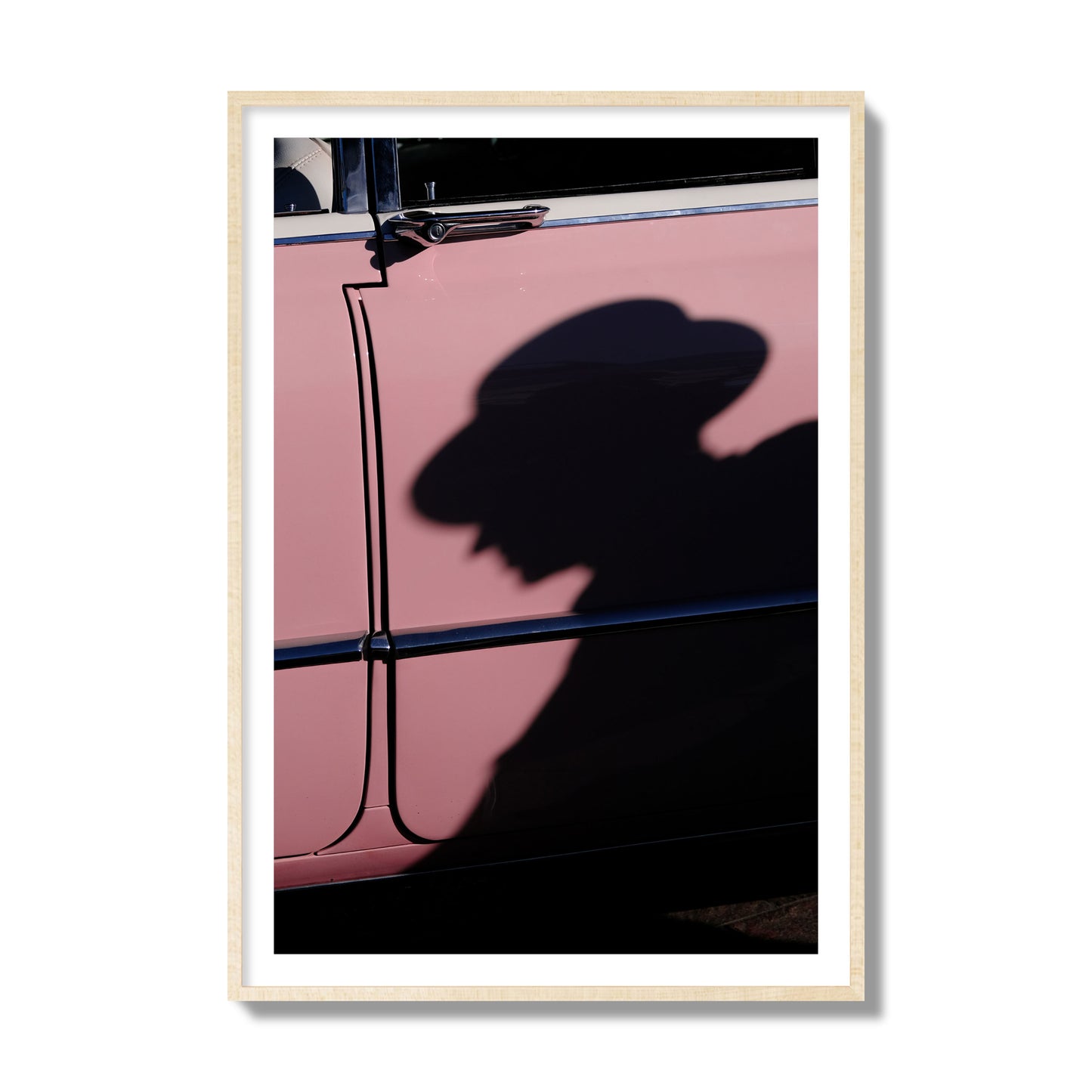 Fine art photograph of a man's shadow cast on a pink retro car, archival pigment print, collector size, natural wood frame.