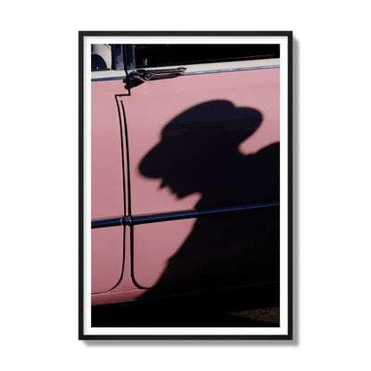 Fine art photograph of a man's shadow cast on a pink retro car, archival pigment print, gallery size, black frame.
