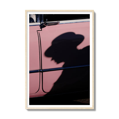 Fine art photograph of a man's shadow cast on a pink retro car, archival pigment print, gallery size, natural wood frame.