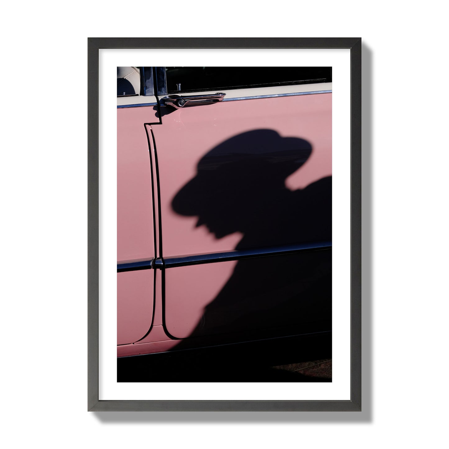Fine art photograph of a man's shadow cast on a pink retro car, archival pigment print, giant size, black frame.