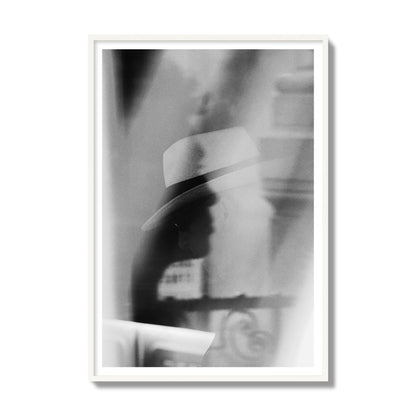 Fine art black and white photograph of multiple faces reflecting in a window, archival pigment print, gallery size, white frame.