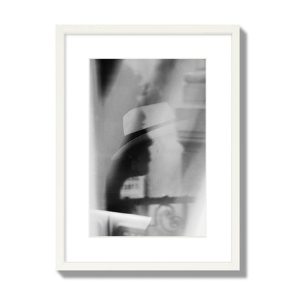 Fine art black and white photograph of multiple faces reflecting in a window, archival pigment print, medium size, white frame.