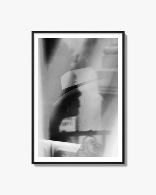 Fine art black and white photograph of multiple faces reflecting in a window, archival pigment print, black frame.