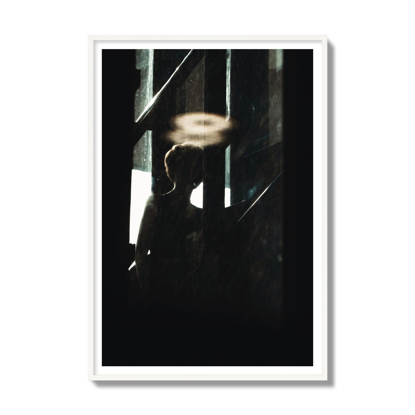 Fine art photograph of a silhouetted woman with a glowing halo light above her head, archival pigment print, gallery size, white frame.
