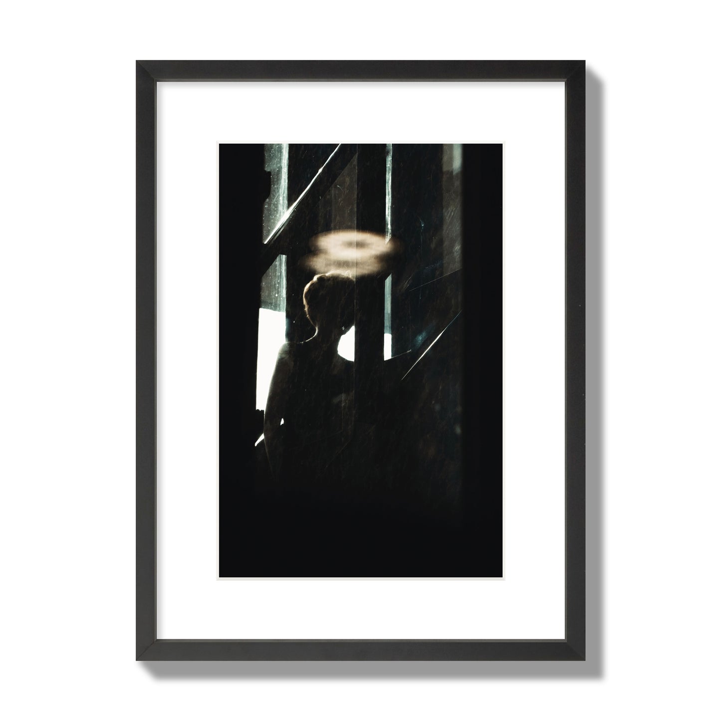 Fine art photograph of a silhouetted woman with a glowing halo light above her head, archival pigment print, medium size, black frame.