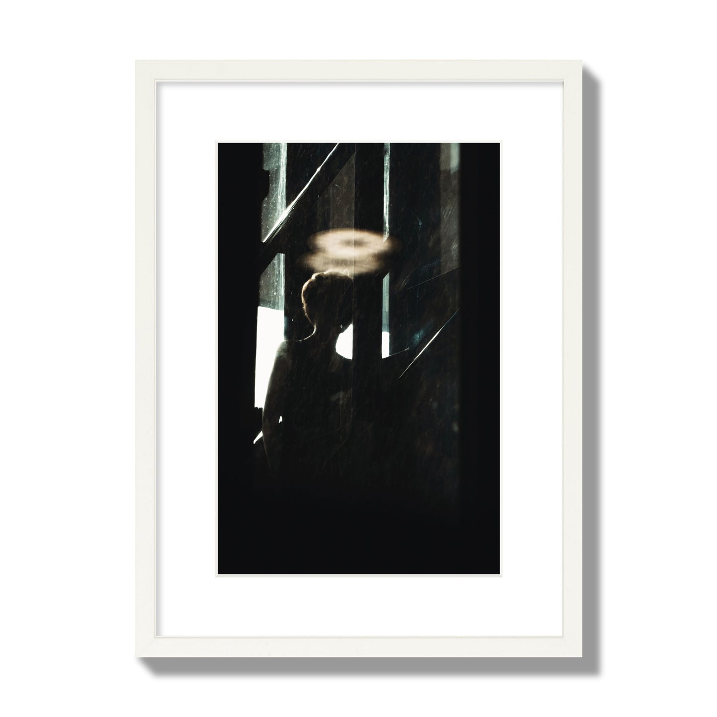 Fine art photograph of a silhouetted woman with a glowing halo light above her head, archival pigment print, medium size, white frame.