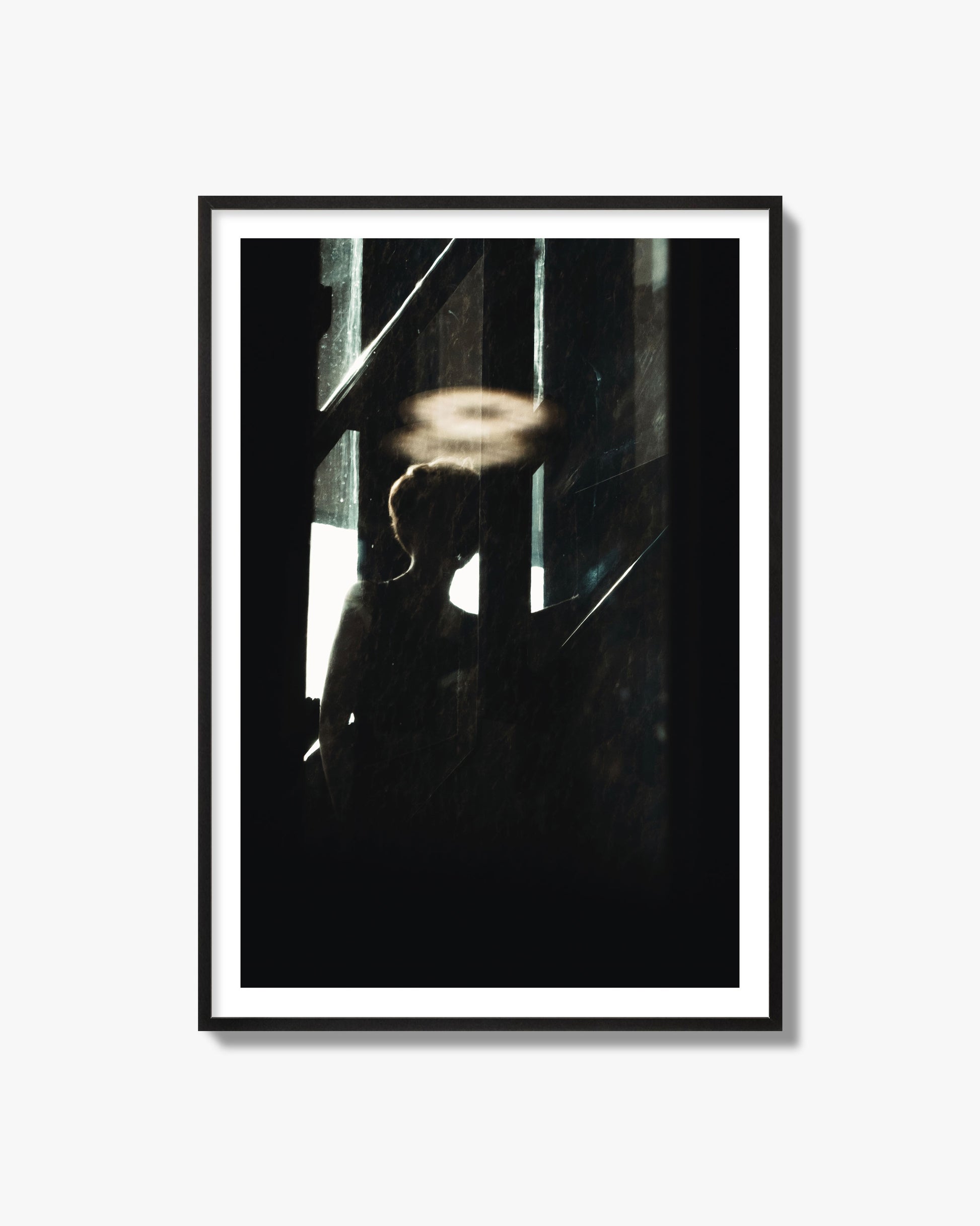 Fine art photograph of a silhouetted woman with a glowing halo light above her head, archival pigment print, black frame.