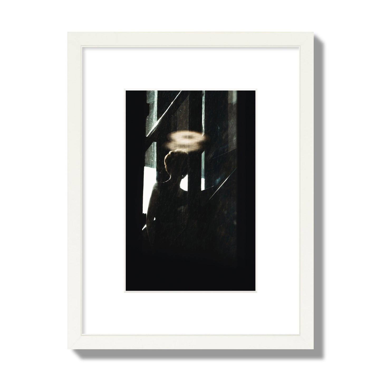 Fine art photograph of a silhouetted woman with a glowing halo light above her head, archival pigment print, small size, white frame.