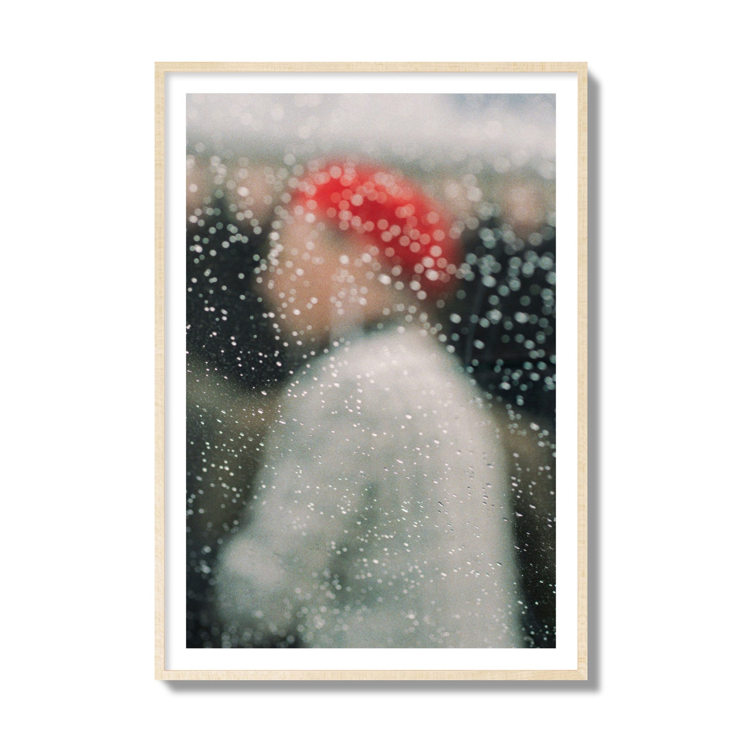Fine art photograph of a woman with a red hat through raindrops on a window, archival pigment print, collector size, natural wood frame.