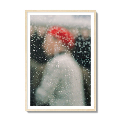 Fine art photograph of a woman with a red hat through raindrops on a window, archival pigment print, collector size, natural wood frame.