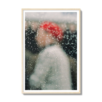 Fine art photograph of a woman with a red hat through raindrops on a window, archival pigment print, gallery size, natural wood frame.