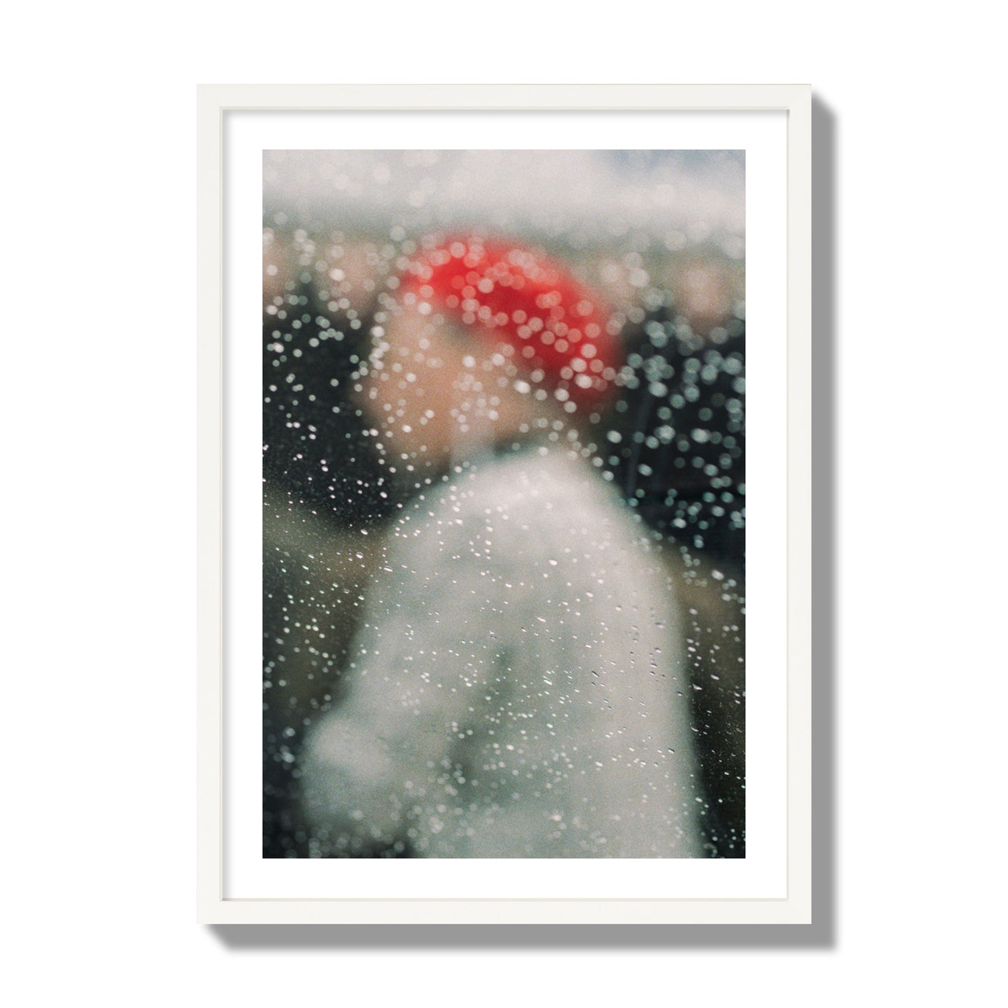 Fine art photograph of a woman with a red hat through raindrops on a window, archival pigment print, giant size, white frame.