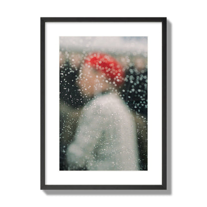 Fine art photograph of a woman with a red hat through raindrops on a window, archival pigment print, large size, black frame.