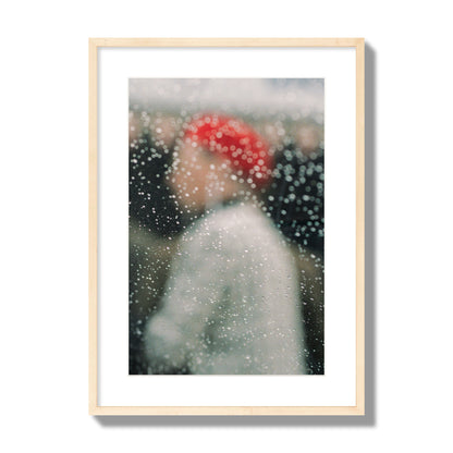 Fine art photograph of a woman with a red hat through raindrops on a window, archival pigment print, large size, natural wood frame.